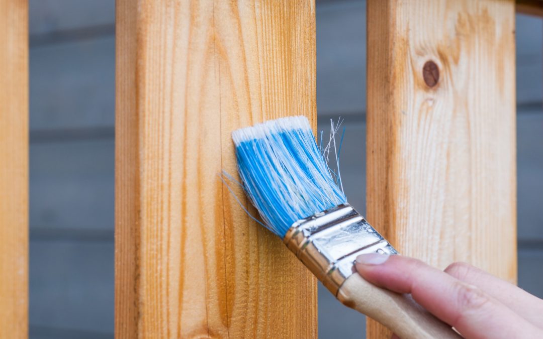 Painter staining a wood fence